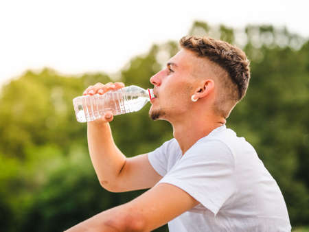 A young attractive sportsman drinking water after training - sport concept