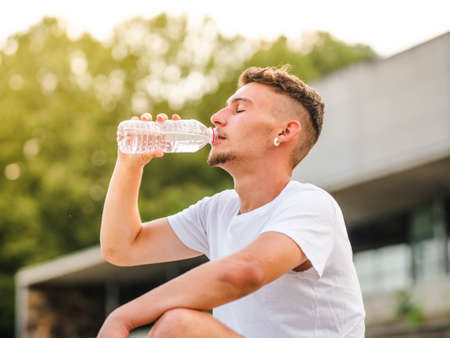 A young attractive sportsman drinking water after training - sport conceptの写真素材
