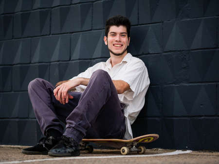 A young attractive male with skateboard posing at camera against a gray backgroundの写真素材