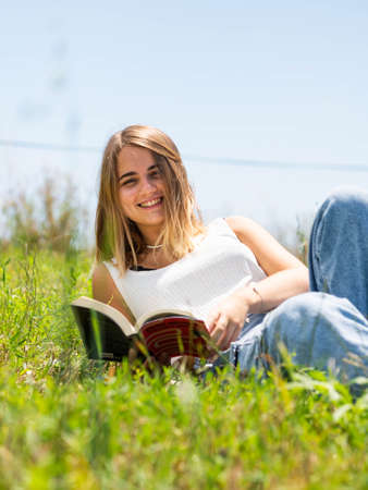 A blonde Caucasian woman reading a book in the parkの写真素材