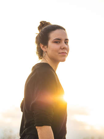 A vertical shot of a young Caucasian woman during the sunset