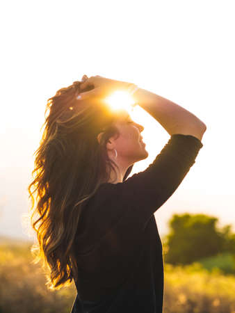 A vertical shot of a young Caucasian woman during the sunsetの写真素材