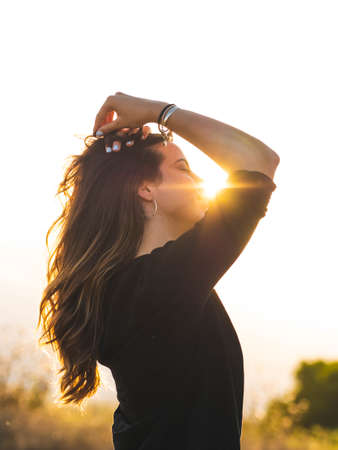 A vertical shot of a young Caucasian woman during the sunsetの写真素材