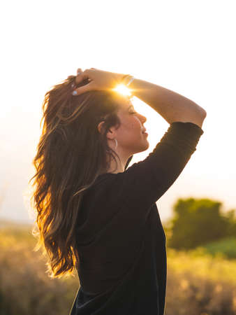 A vertical shot of a young Caucasian woman during the sunsetの写真素材