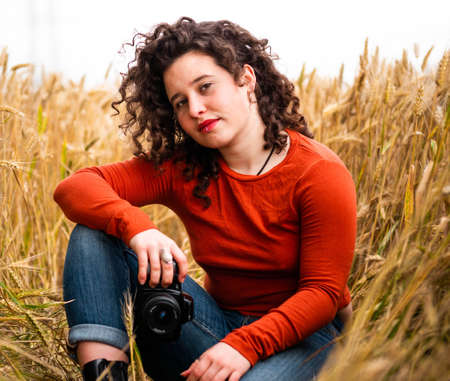 A shallow focus shot of a beautiful young female with a professional photo cameraの写真素材