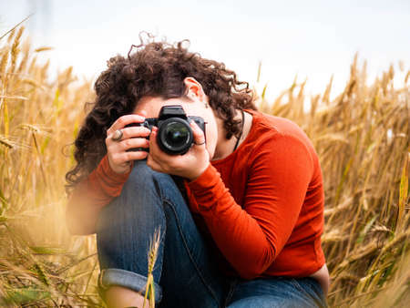 A shallow focus shot of a beautiful young female with a professional photo camera
