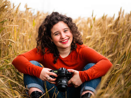 A shallow focus shot of a beautiful young female with a professional photo cameraの写真素材