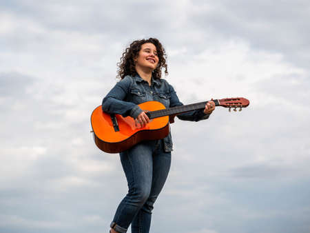 A shallow focus shot of a beautiful young female playing guitar in a wheat fieldの写真素材