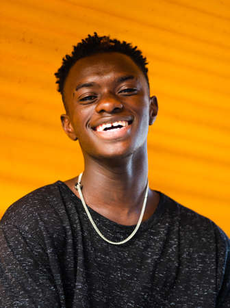 A shallow focus shot of a young black male on a yellow wall backgroundの写真素材