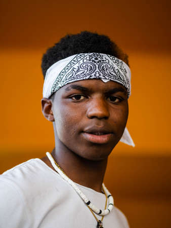 A shallow focus shot of a young black male on a yellow wall backgroundの写真素材