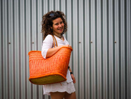 A happy Caucasian woman with curly hair and a big bagの写真素材