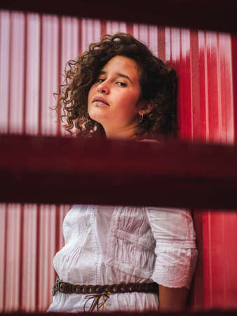 A shallow focus shot of a Caucasian female with curly hair on red background