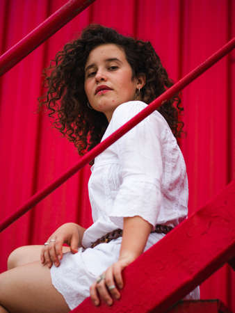 A shallow focus shot of a Caucasian female with curly hair on red backgroundの写真素材