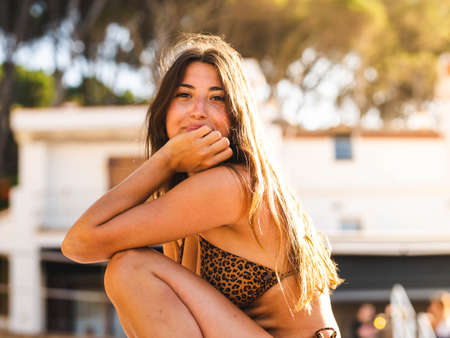 attractive Caucasian woman in a bikini smiling. Caucasian female with leopard print bikini sitting on the beachの写真素材