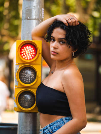 Brazilian woman with headphones in the street. woman sitting on the roof with a modern building in the backgroundの写真素材