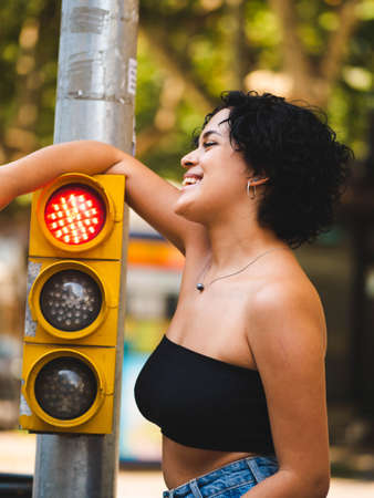 Brazilian woman with headphones in the street. woman sitting on the roof with a modern building in the backgroundの写真素材