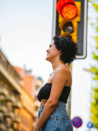 Brazilian woman with headphones in the street. woman sitting on the roof with a modern building in the backgroundの写真素材