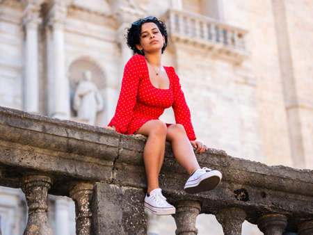 young female with a red dress. Cheerful curly hair girlの写真素材