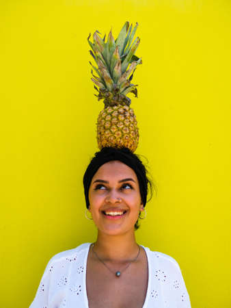 attractive Brazilian female with pineapple on yellow background. attractive Brazilian female with pineapple and juice on yellow backgroundの写真素材