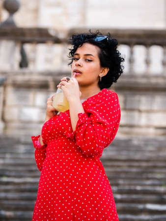 Brazilian female with a red dress. Young woman drinking juiceの写真素材