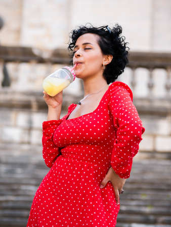 Brazilian female with a red dress. Young woman drinking juiceの写真素材