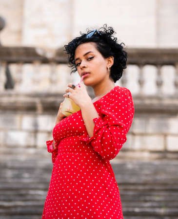 Brazilian female with a red dress. Young woman drinking juiceの写真素材