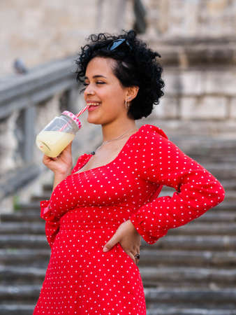 Brazilian female with a red dress. Young woman drinking juiceの写真素材