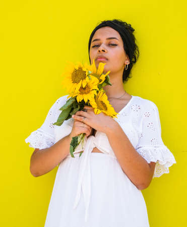 attractive Brazilian female with sunflowers on yellow background. attractive Brazilian female with sunflowers in the parkの写真素材