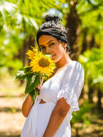 attractive Brazilian female with sunflowers on yellow background. attractive Brazilian female with sunflowers in the parkの写真素材