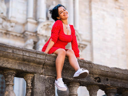 young female with a red dress. Cheerful curly hair girlの写真素材