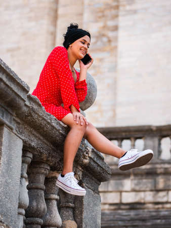 Business woman with red dress in outdoors talking on mobile phoneの写真素材
