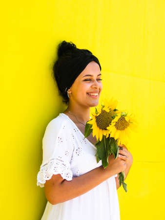 attractive Brazilian female with sunflowers on yellow background. attractive Brazilian female with sunflowers in the parkの写真素材