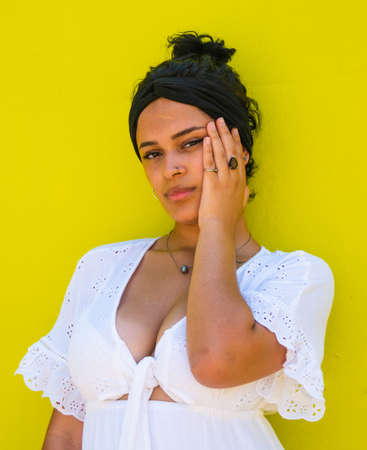 attractive Brazilian female with sunglasses on yellow background. Brazilian female with white dress on yellow backgroundの写真素材