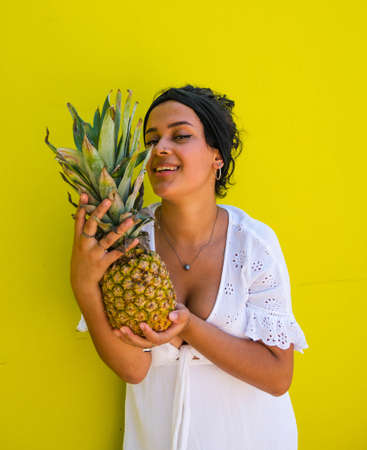 attractive Brazilian female with pineapple on yellow background. attractive Brazilian female with pineapple and juice on yellow backgroundの写真素材