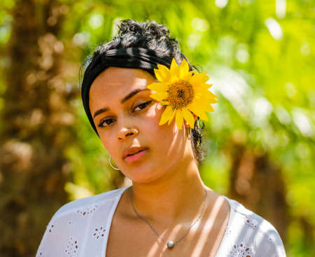 attractive Brazilian female with sunflowers on yellow background. attractive Brazilian female with sunflowers in the parkの写真素材