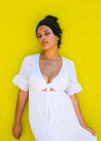 attractive Brazilian female with sunglasses on yellow background. Brazilian female with white dress on yellow backgroundの写真素材