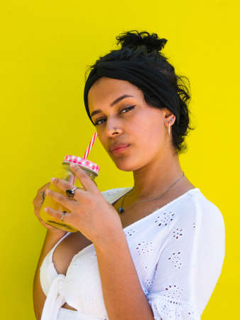attractive Brazilian female with pineapple on yellow background. attractive Brazilian female with pineapple and juice on yellow backgroundの写真素材