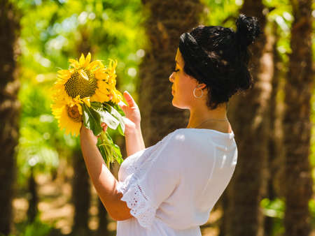 attractive Brazilian female with sunflowers on yellow background. attractive Brazilian female with sunflowers in the parkの写真素材