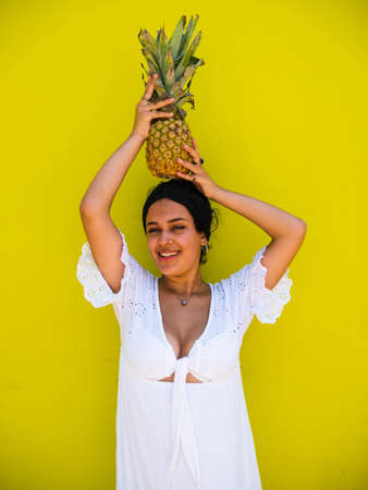 attractive Brazilian female with pineapple on yellow background. attractive Brazilian female with pineapple and juice on yellow backgroundの写真素材