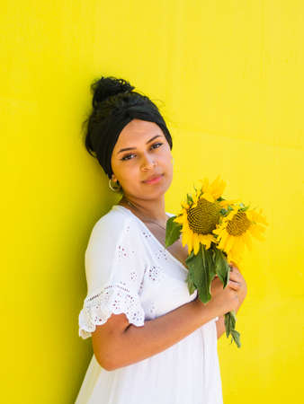 attractive Brazilian female with sunflowers on yellow background. attractive Brazilian female with sunflowers in the parkの写真素材