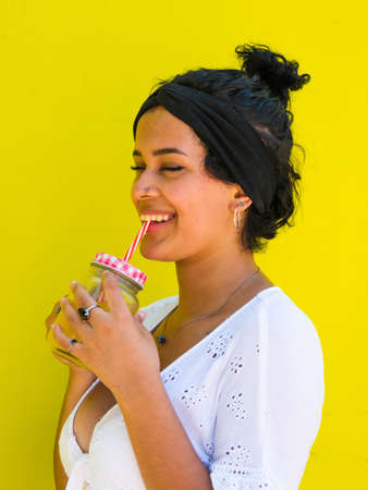 attractive Brazilian female with pineapple on yellow background. attractive Brazilian female with pineapple and juice on yellow backgroundの写真素材
