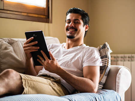 man using digital tablet. Man sitting in sofa an his tabletの写真素材