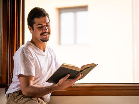 Man sitting at home and reading bookの写真素材