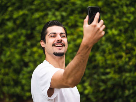 Man looking at his cellphone smartphone making selfieの写真素材