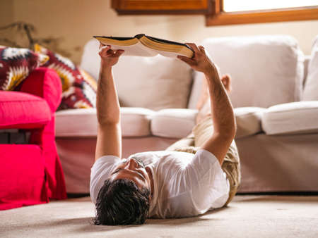 Man sitting at home and reading bookの写真素材