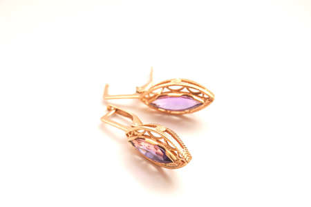 Age-old Gold Earrings with light violet gems close-up isolated on whiteの写真素材