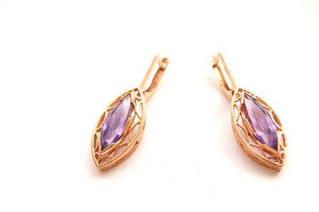 Age-old Gold Earrings with light violet gem close-up isolated on whiteの写真素材