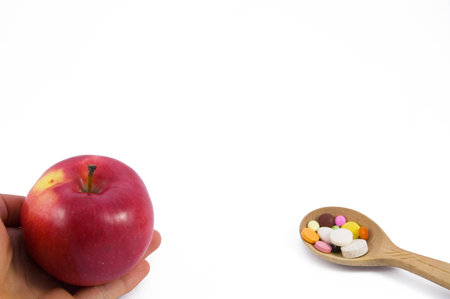 Proposed red apple on hand and spoon full of pillsの写真素材