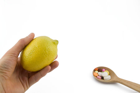 Proposed lemon on hand and spoon full of pillsの写真素材