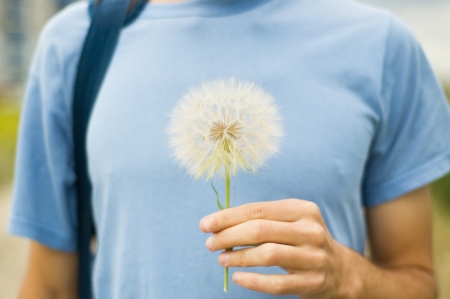 Man in blue wearing is hanging white dandelion on handの写真素材